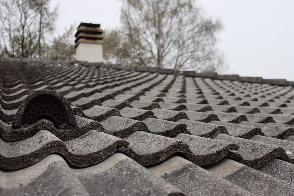 Close-up of ventilation pipe on house roof top covered with gray cement roofing tiles